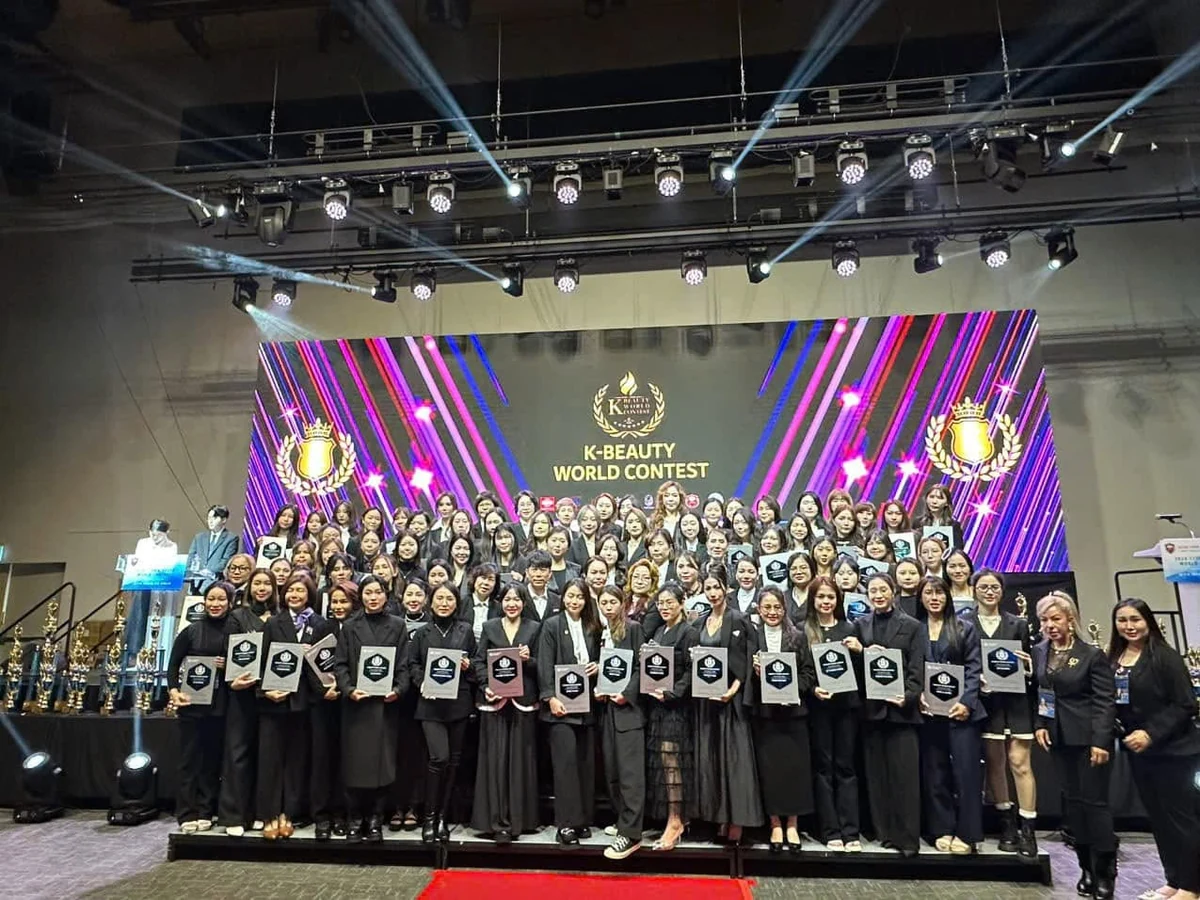 Ảnh tập thể trên sân khấu K-Beauty World Contest, nhiều người cầm chứng nhận.